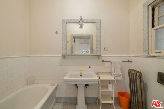 bathroom featuring tile walls, tile patterned floors, radiator heating unit, and a tub