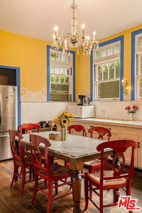 dining room featuring an inviting chandelier, a wealth of natural light, and dark hardwood / wood-style flooring