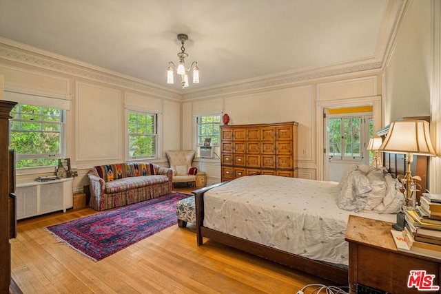 bedroom with crown molding, light hardwood / wood-style floors, radiator, and a notable chandelier