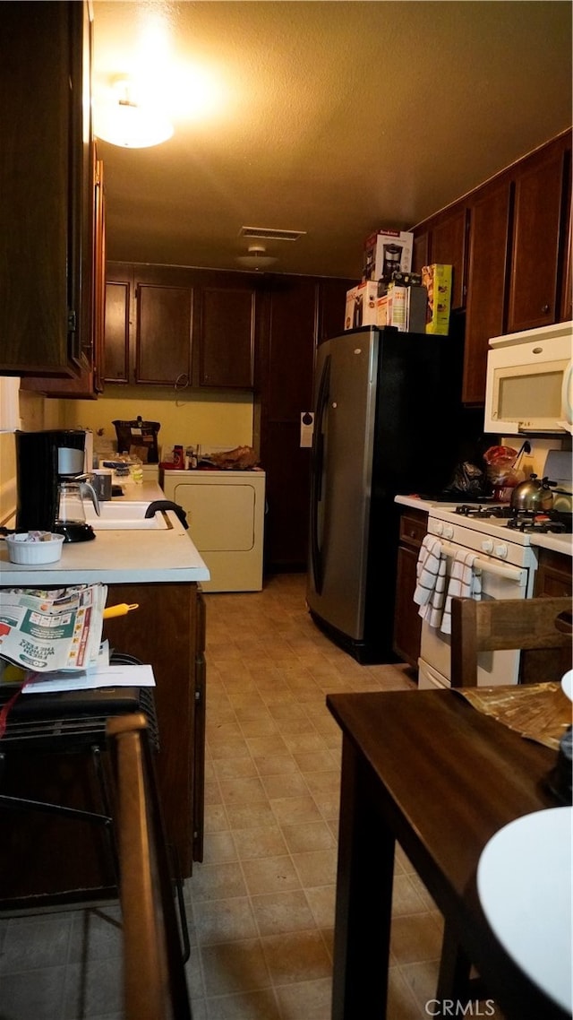 kitchen with a textured ceiling, white appliances, and dark brown cabinets