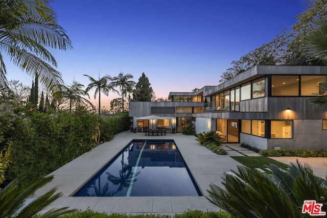 pool at dusk featuring a patio area