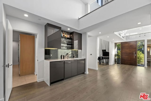 bar with wood-type flooring and stainless steel dishwasher