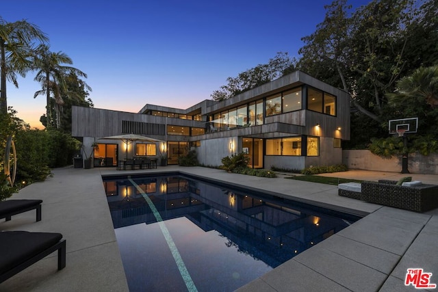 pool at dusk featuring a patio