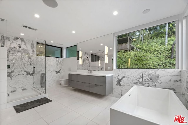 full bathroom with tile walls, tile patterned flooring, independent shower and bath, vanity, and toilet