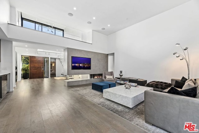 living room with a towering ceiling and dark hardwood / wood-style floors