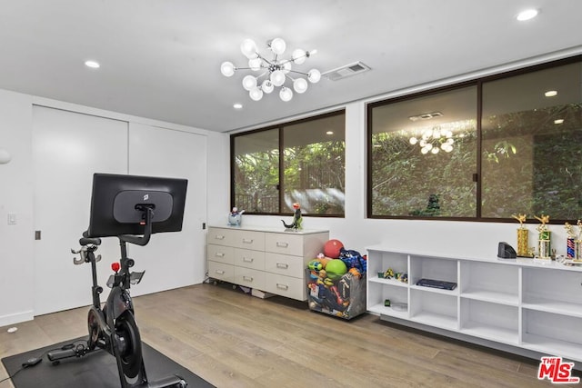 workout room featuring light hardwood / wood-style flooring, floor to ceiling windows, and an inviting chandelier