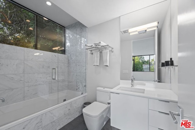 full bathroom featuring shower / bath combination with glass door, vanity, and toilet