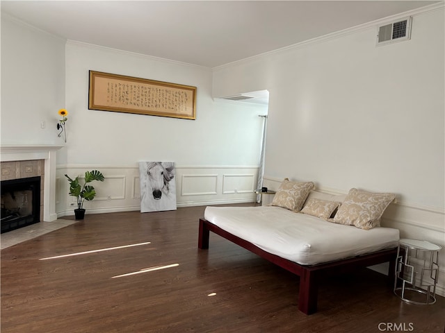 living room with ornamental molding, a tiled fireplace, and dark wood-type flooring