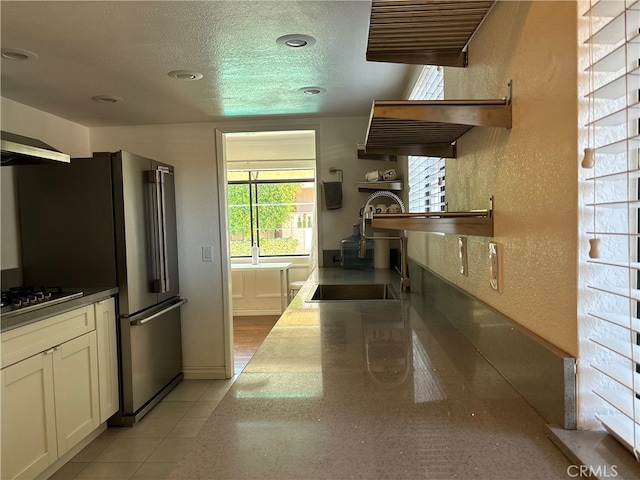 kitchen featuring black gas cooktop, white cabinets, a textured ceiling, and light tile patterned flooring