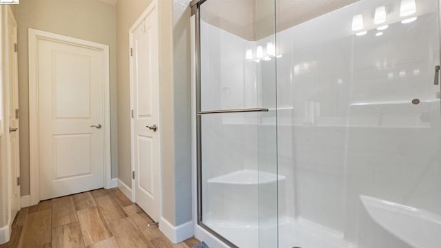 bathroom featuring a shower with shower door and hardwood / wood-style floors