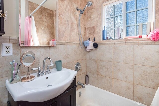 bathroom featuring tile walls, vanity, and shower / tub combo