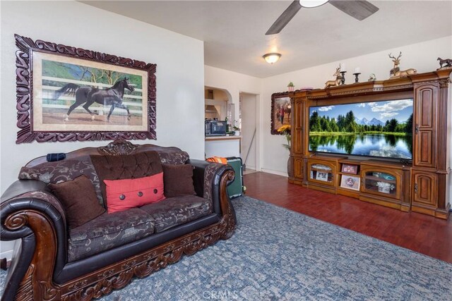 living room featuring ceiling fan and dark hardwood / wood-style flooring