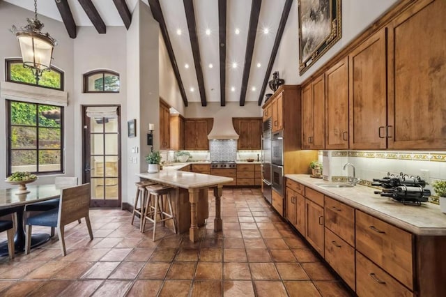 kitchen with tasteful backsplash, a breakfast bar, sink, beamed ceiling, and hanging light fixtures