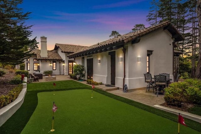 back house at dusk featuring a patio