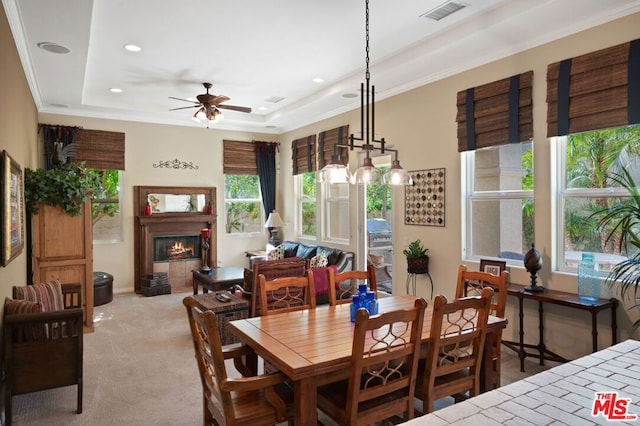 carpeted dining room featuring ceiling fan, a raised ceiling, and ornamental molding