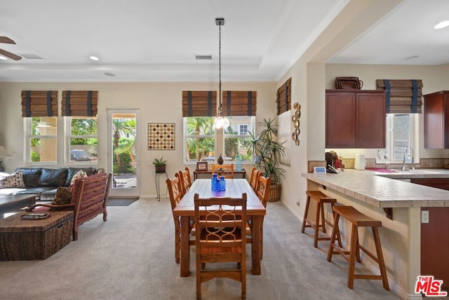 dining space with light carpet, crown molding, sink, and ceiling fan