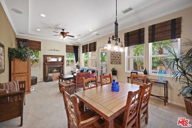 dining space featuring ceiling fan with notable chandelier, light colored carpet, plenty of natural light, and ornamental molding