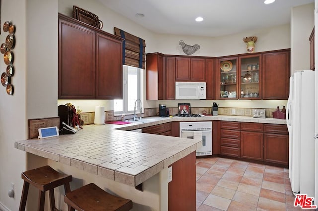 kitchen featuring white appliances, kitchen peninsula, and a breakfast bar area