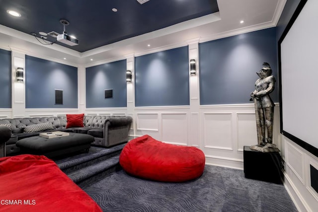 cinema with ornamental molding, a raised ceiling, and carpet flooring