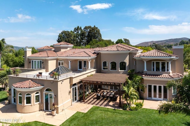 rear view of house with a mountain view, a lawn, a patio area, and french doors