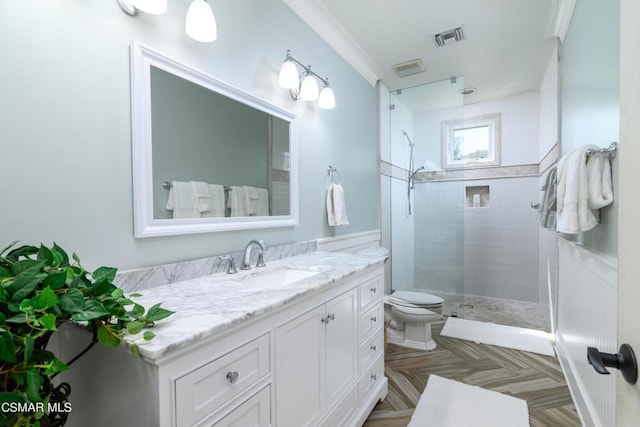 bathroom featuring crown molding, vanity, toilet, and a tile shower