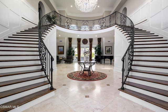 entryway with crown molding, a notable chandelier, and a towering ceiling