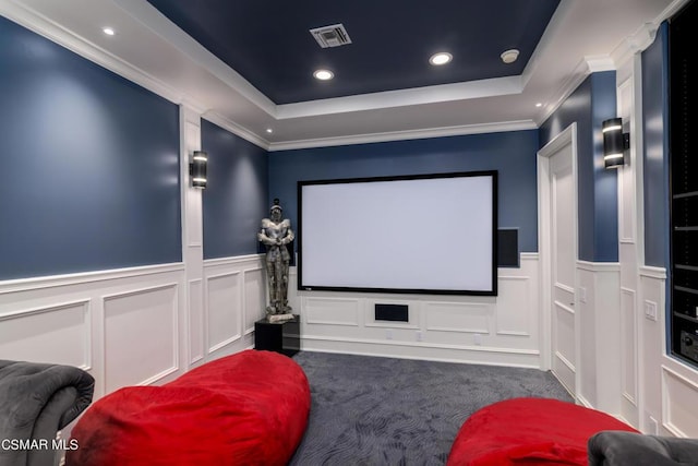 carpeted cinema featuring ornamental molding and a tray ceiling