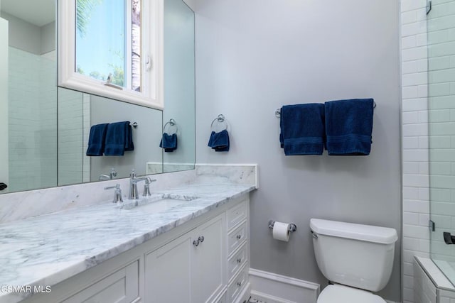 bathroom featuring vanity, toilet, and a tile shower