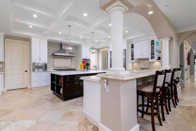 kitchen featuring white cabinetry, appliances with stainless steel finishes, wall chimney range hood, and kitchen peninsula