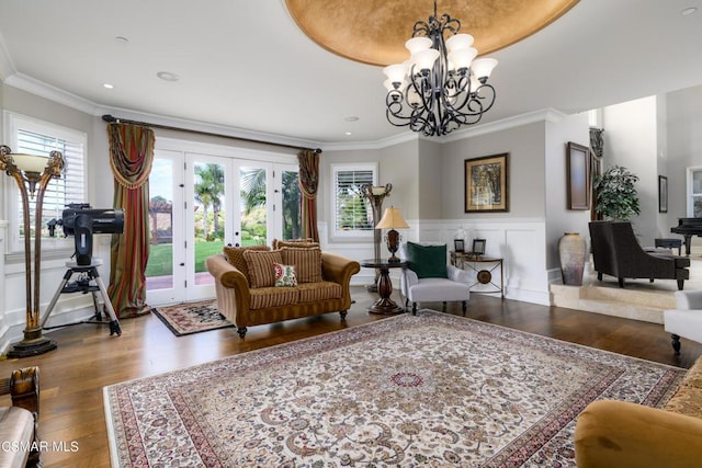 living room with crown molding, hardwood / wood-style floors, a chandelier, and french doors