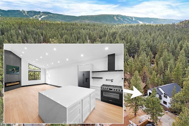 exterior space featuring gas stove, a kitchen island, stainless steel refrigerator with ice dispenser, a mountain view, and white cabinets