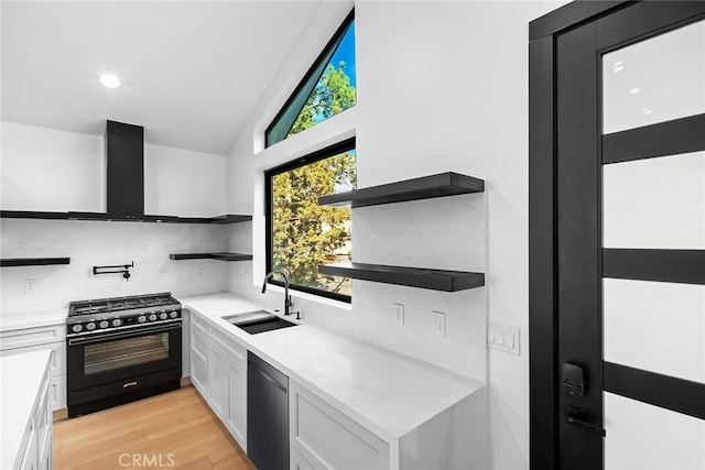 kitchen with sink, wall chimney exhaust hood, stainless steel dishwasher, high end stove, and white cabinets