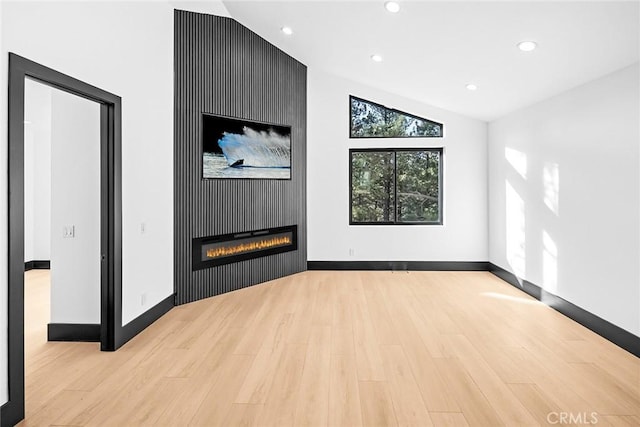 unfurnished living room featuring light hardwood / wood-style flooring, a fireplace, and vaulted ceiling