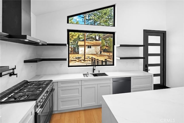 kitchen featuring appliances with stainless steel finishes, wall chimney exhaust hood, sink, light hardwood / wood-style flooring, and white cabinetry