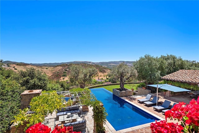 view of swimming pool with a mountain view and a patio area