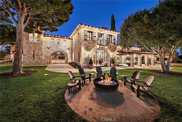 rear view of property with a yard, a patio, a balcony, and a fire pit