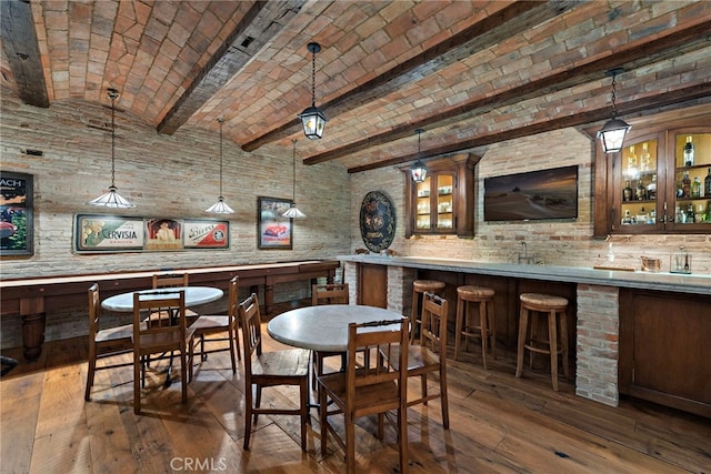 bar with tasteful backsplash, dark wood-type flooring, pendant lighting, vaulted ceiling, and brick ceiling