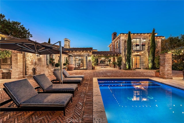 pool at dusk featuring a patio area