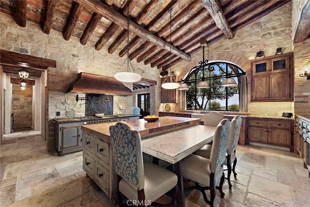 kitchen with beamed ceiling, a kitchen island, high vaulted ceiling, butcher block countertops, and premium range hood