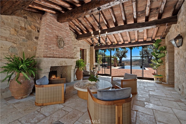 view of patio / terrace with a water view, a lanai, and an outdoor stone fireplace