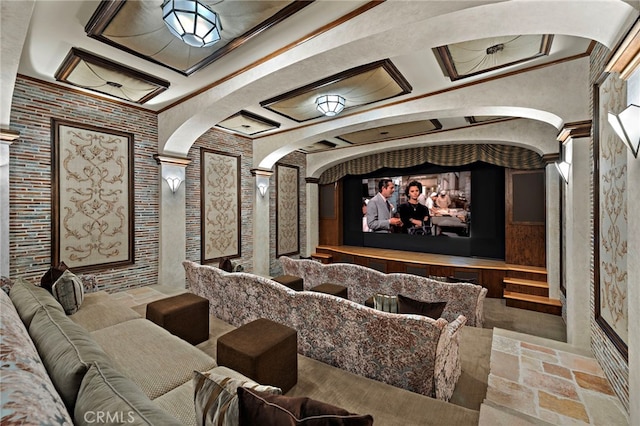 home theater room featuring ornamental molding, a multi sided fireplace, coffered ceiling, and ornate columns