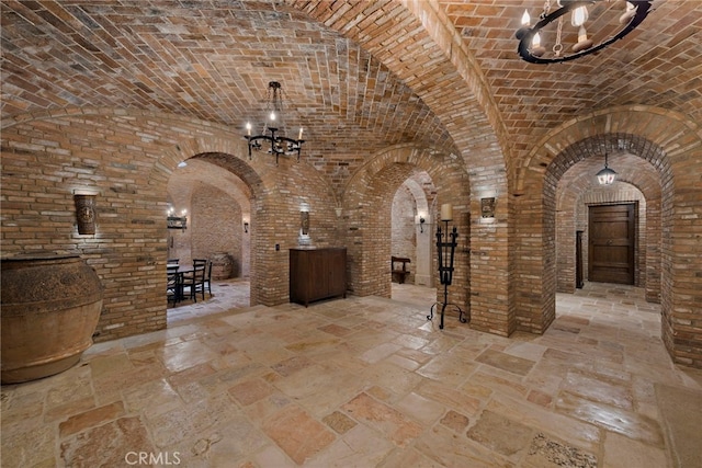 wine cellar with a notable chandelier, brick ceiling, and brick wall