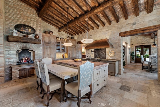 dining room featuring a brick fireplace, beamed ceiling, high vaulted ceiling, and wooden ceiling