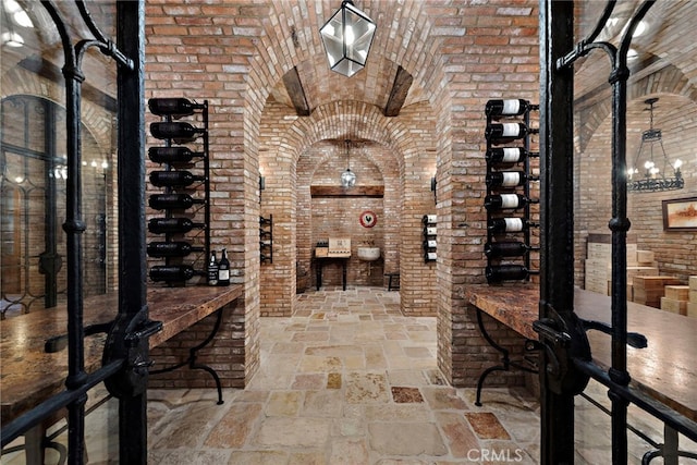 wine cellar with brick ceiling, a chandelier, and brick wall