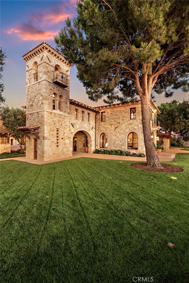 view of front facade with a balcony and a lawn