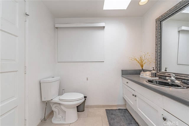 bathroom featuring tile patterned floors, a skylight, vanity, and toilet