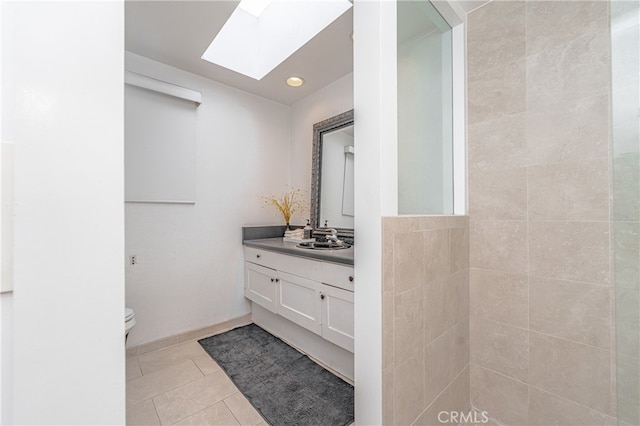 bathroom featuring vanity, toilet, a skylight, and tile patterned floors