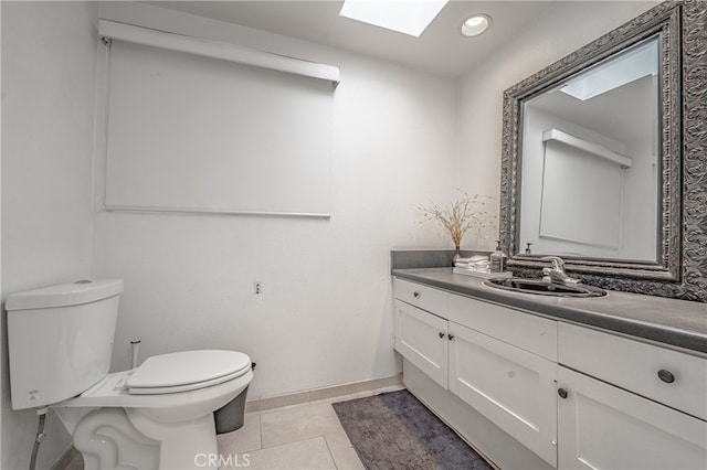 bathroom featuring tile patterned flooring, a skylight, vanity, and toilet