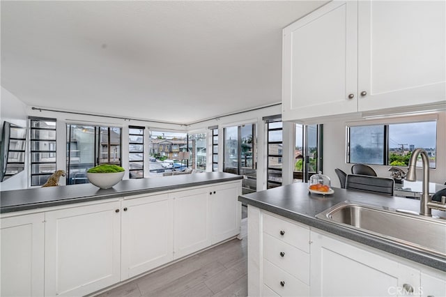 kitchen featuring white cabinetry, sink, light hardwood / wood-style flooring, and a wealth of natural light