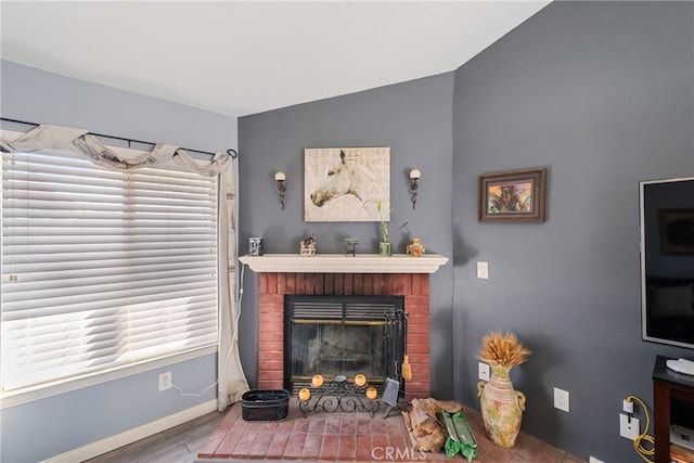 living room featuring vaulted ceiling, a fireplace, hardwood / wood-style floors, and a healthy amount of sunlight